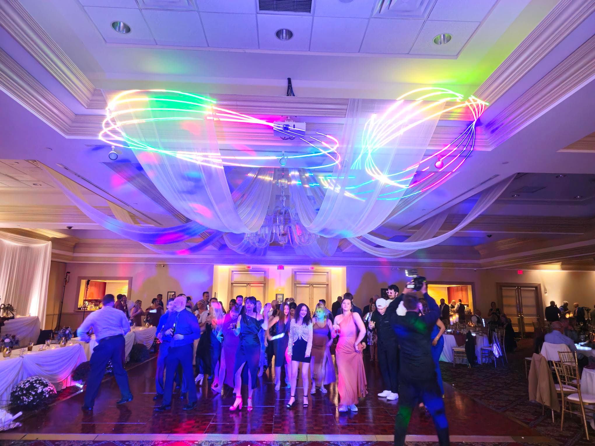 Wedding guests dancing beneath colorful moving lights at a BT Sound reception